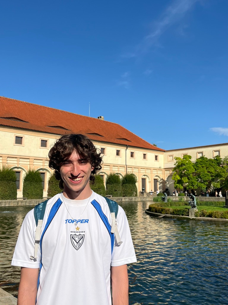 Tomás Korenblit smiling in a white football shirt beside a garden pond
