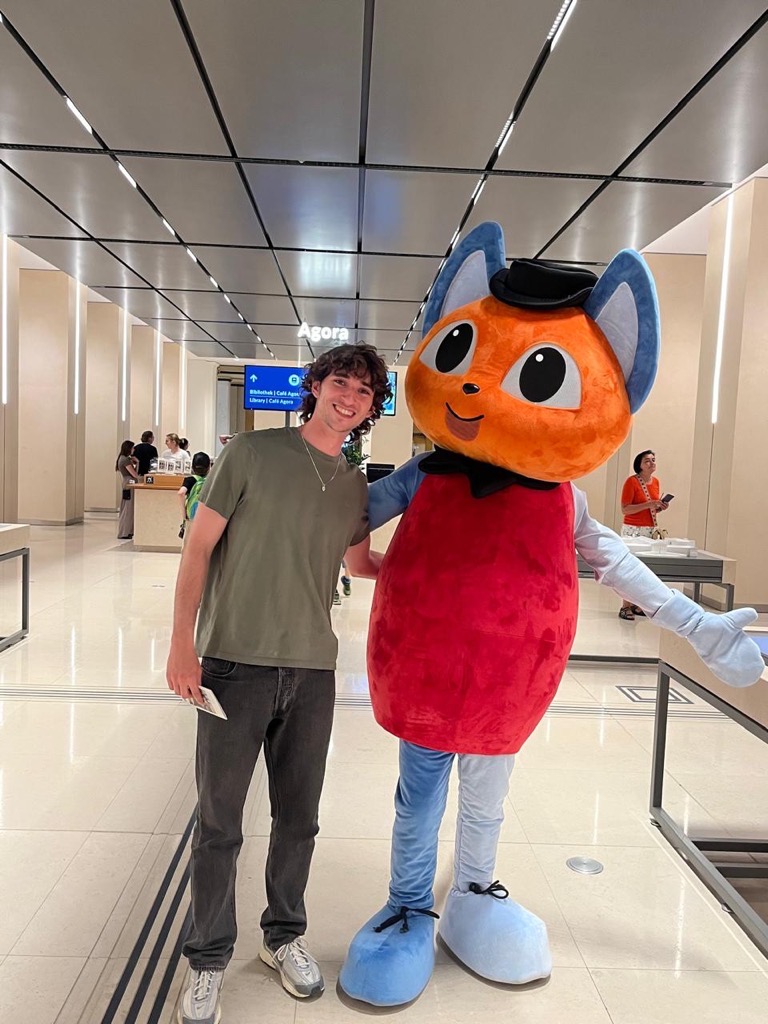 Tomás Korenblit standing beside a large orange mascot